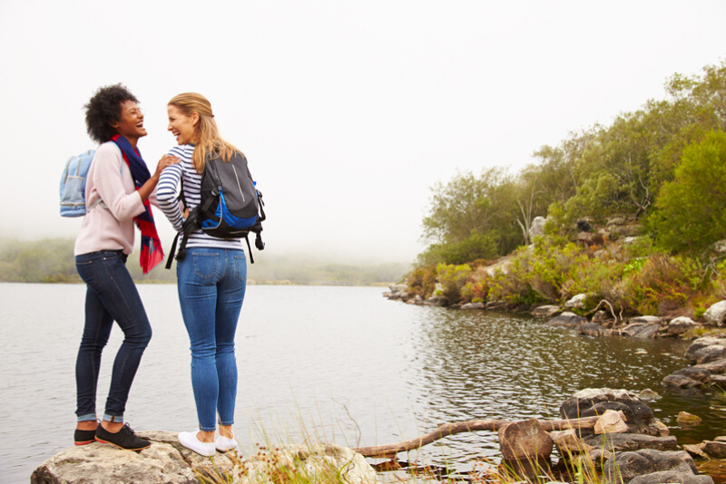Two female friends hiking by a lake